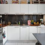 Delantal de mosaico en cocina moderna con encimera de madera.